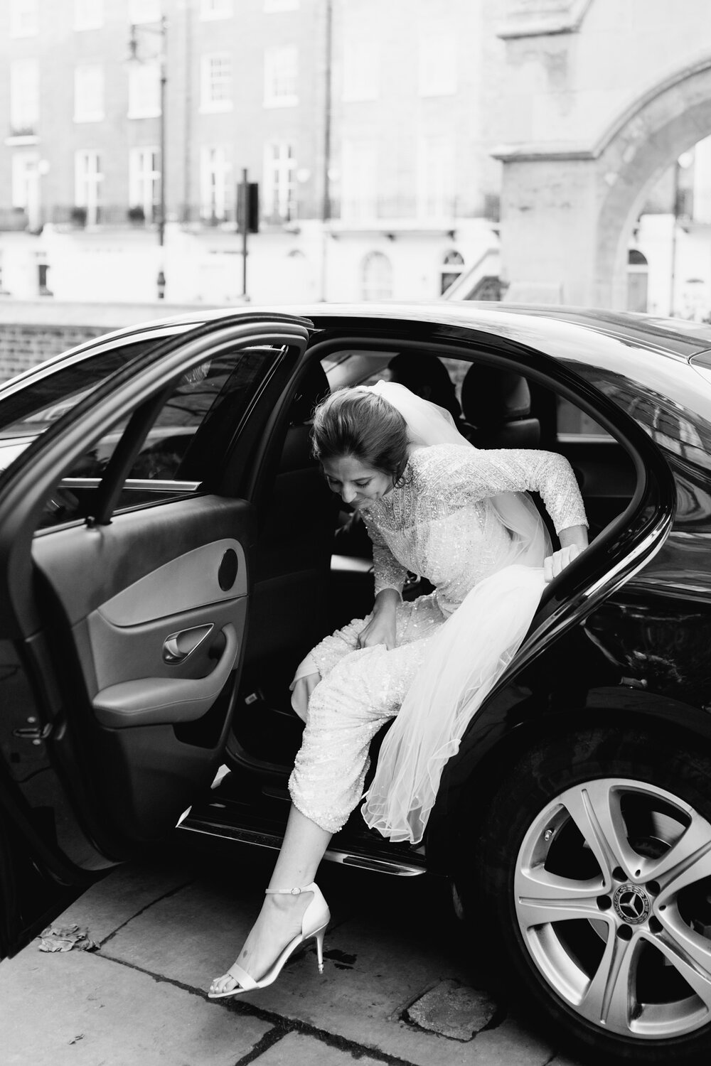 Elegant an editorial black and white photograph of the bride exiting her car as the arrives at St Pauls in Knightsbridge