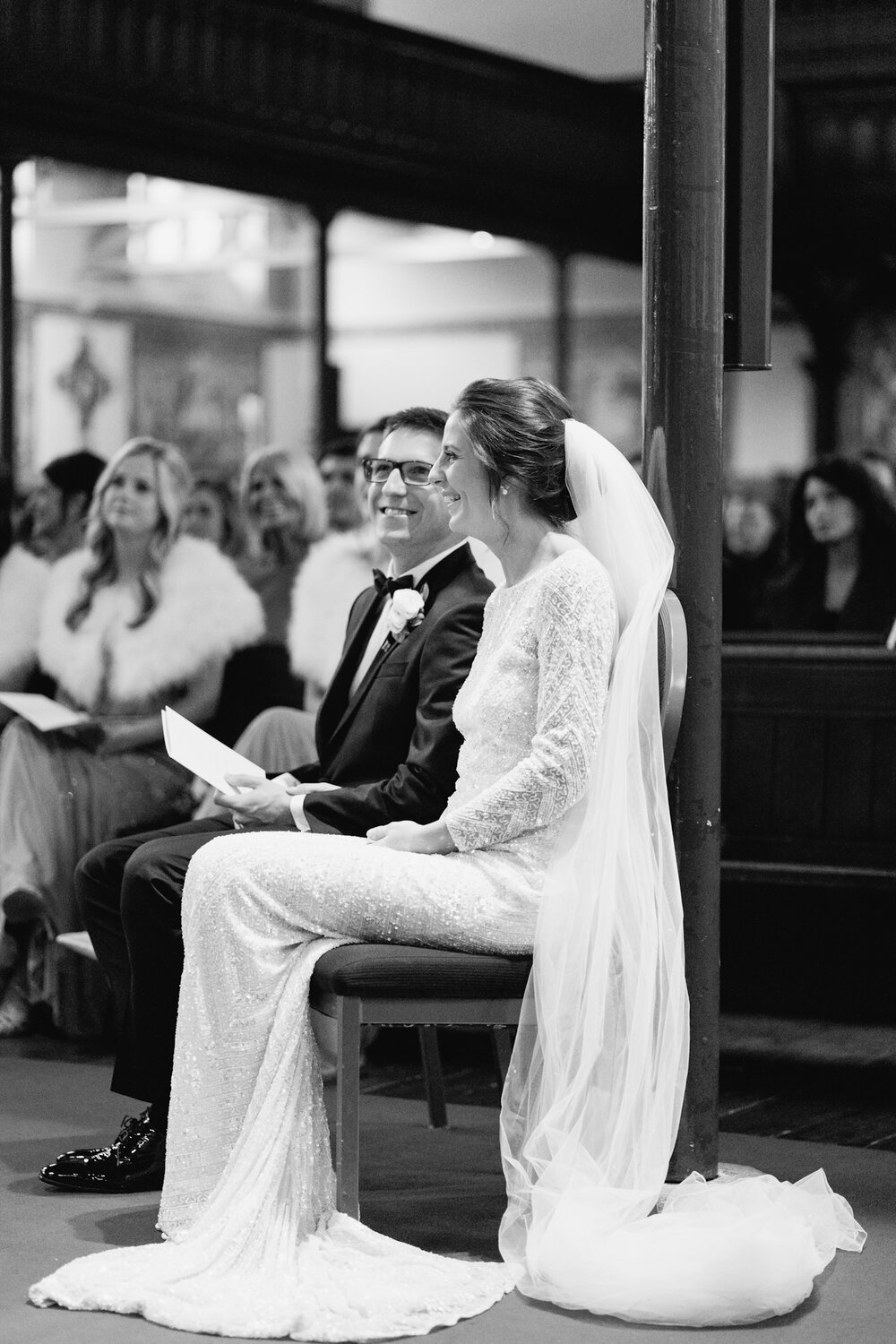 Bride and groom sit during wedding service at St Pauls Knightsbridge while readings take place