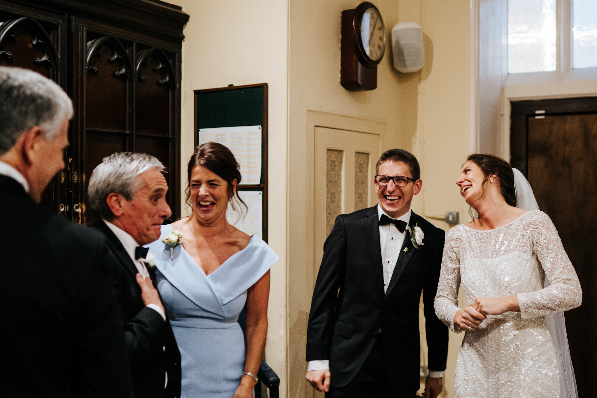 Bride, groom, bride's parents and groom's father share a moment of joy in the church moments before the register is signed