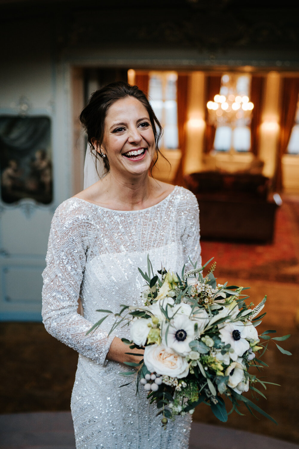 Portrait of the bride on the stairs at Savile Club London as groom, off-frame, makes her smile