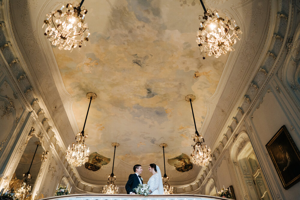 Posed portrait of the bride and groom with eloquent chandeliers at Savile Club London
