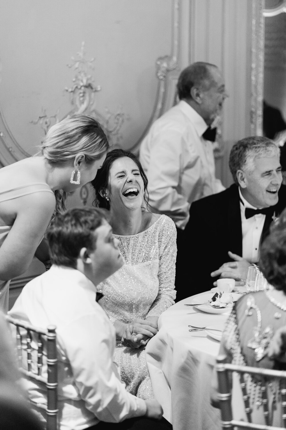 Bride cannot contain her laughter as she speaks to one of her bridesmaids