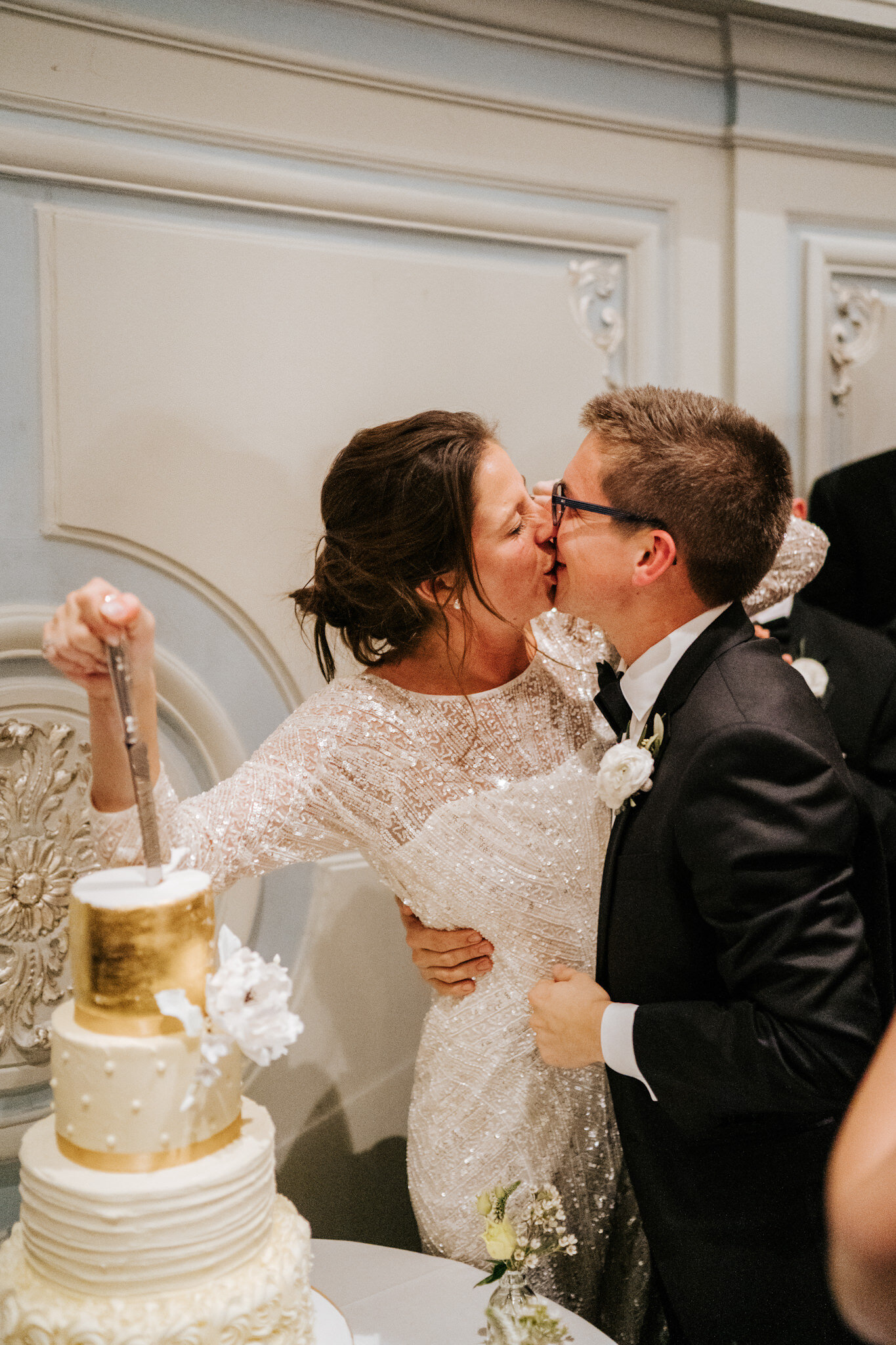 Bride and groom kiss as bride pierces wedding cake with a knife during cake cutting