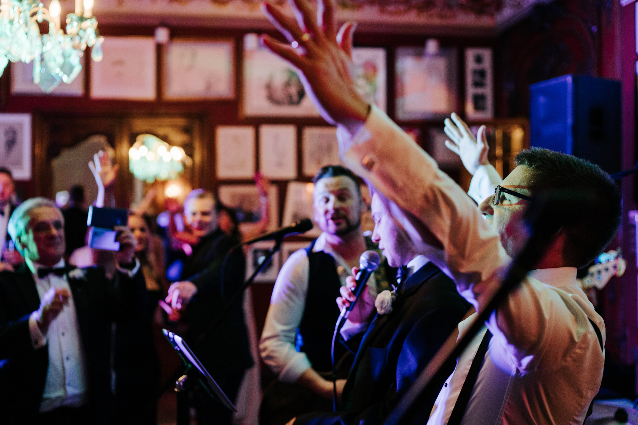 Groom throws his hands up in the air as he takes over the microphone and signs a song at his Savile Club London Wedding
