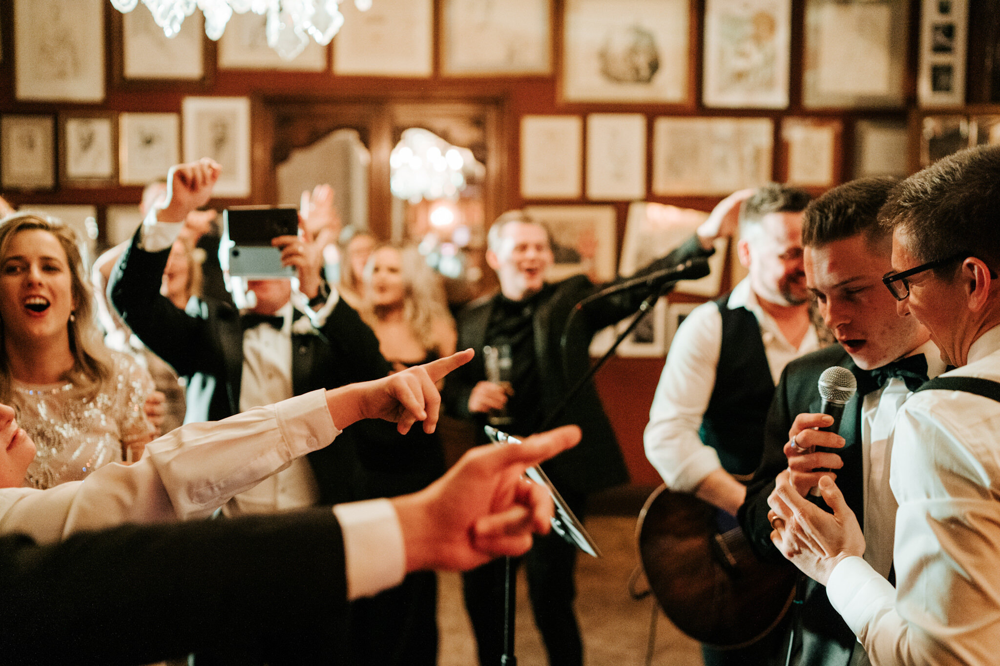 Best man joins groom on the dancefloor microphone to sing a song as guests have a blast and dance at Savile Club London