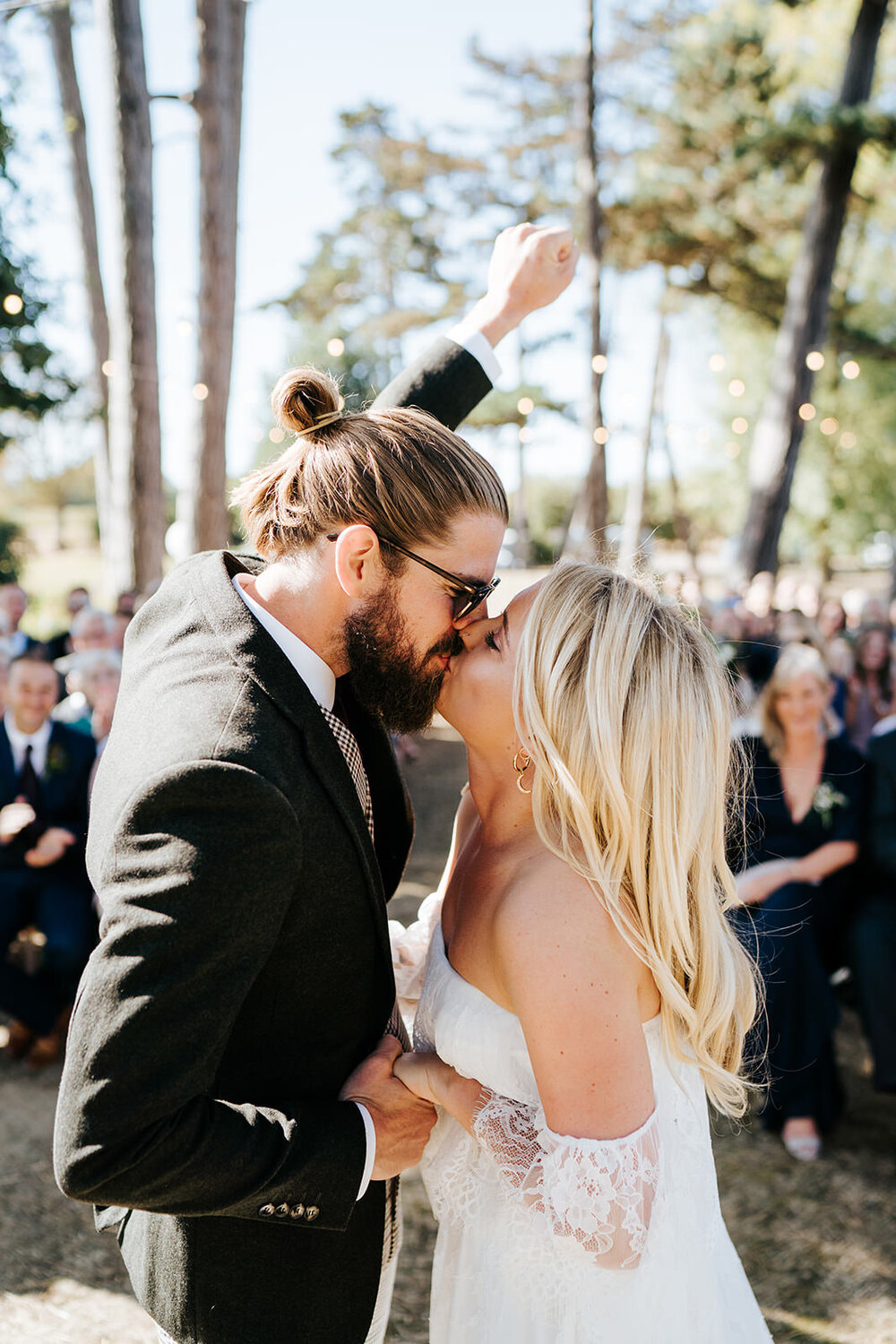 Groom pumps his fist into the air as he kisses his bohemian bride for very first time during civil tipi wedding ceremony