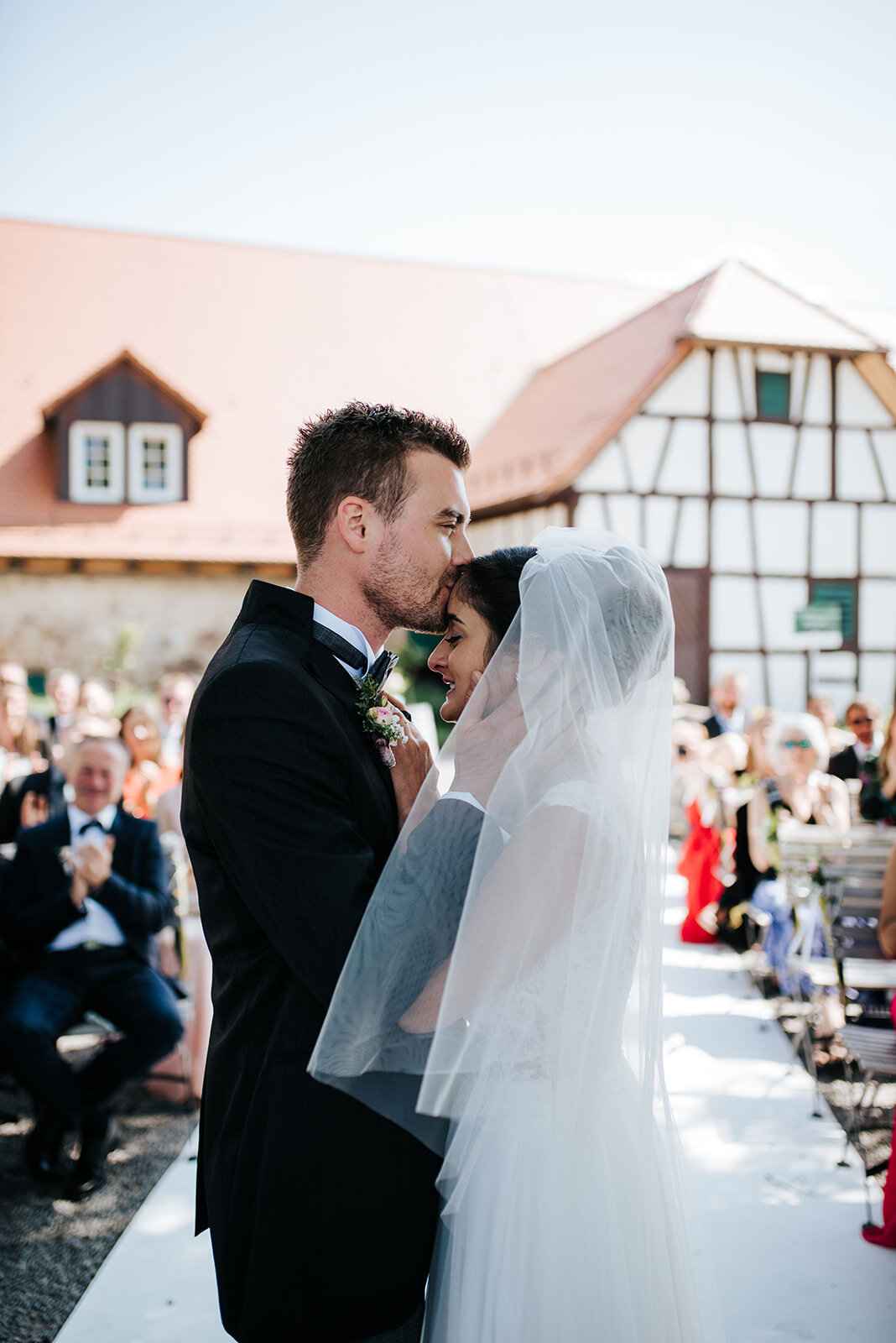 Groom kisses his bride on the forehead seconds after the first kiss during wedding ceremony at Schloss Staufenberg in Germany