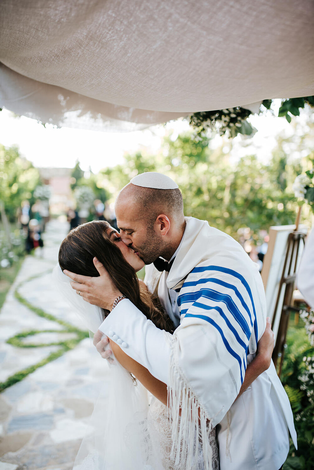 Groom holds bride's head and leans her back gently as he gives her a kiss during Jewish wedding ceremony in Puerto Rico 