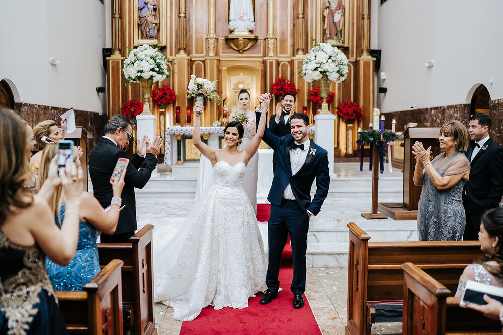 Bride and groom both celebrate and throw their hands up in the air after their Puerto Rican Christmas Wedding ceremony concludes 