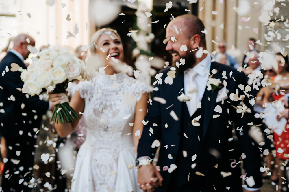 Bride and groom, out of focus, walk into sea of confetti after wedding ceremony in Richmond London
