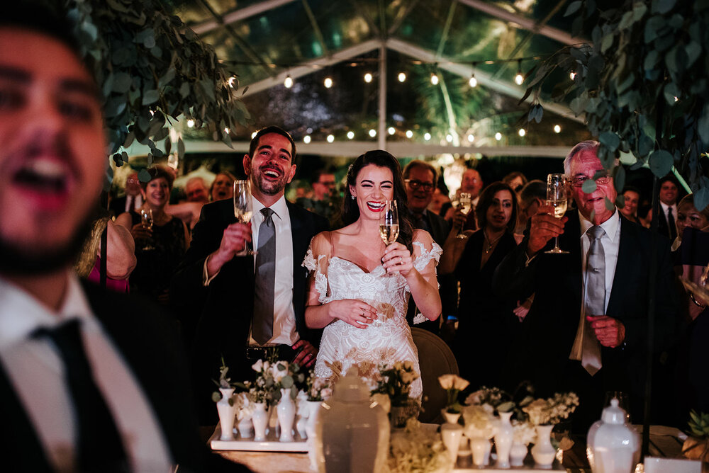 Bride and groom, centre, raise a toast to their guests during beautiful, ocean-front marquee wedding in Puerto Rico