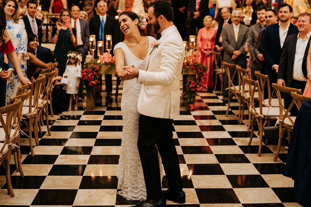 Bride and groom smile and look at their guests as they have their first dance on checkered tile floor at Puerto Rican El Convento Hotel