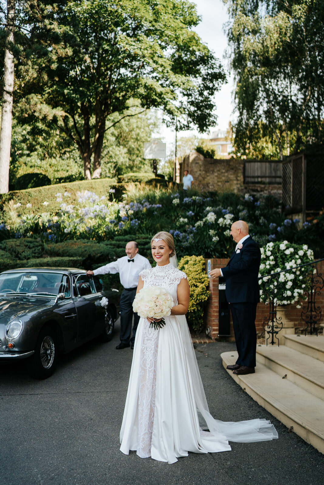 Bride holds her bouquet of white roses as she waits outside of The Petersham to leave for her wedding ceremony