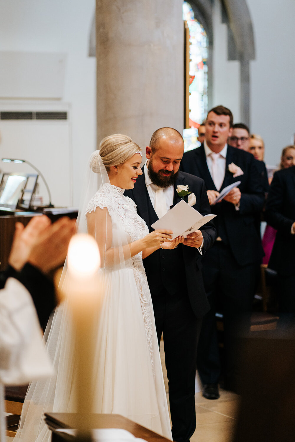 Bride and groom stand next to each other and sing one of the hymns during wedding at St Matthias wedding on Richmond Hill in London