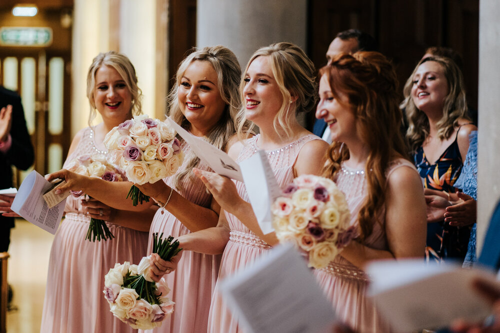 Bridesmaids clap and cheer as the couple make their entrance into the room at Pembroke Lodge wedding