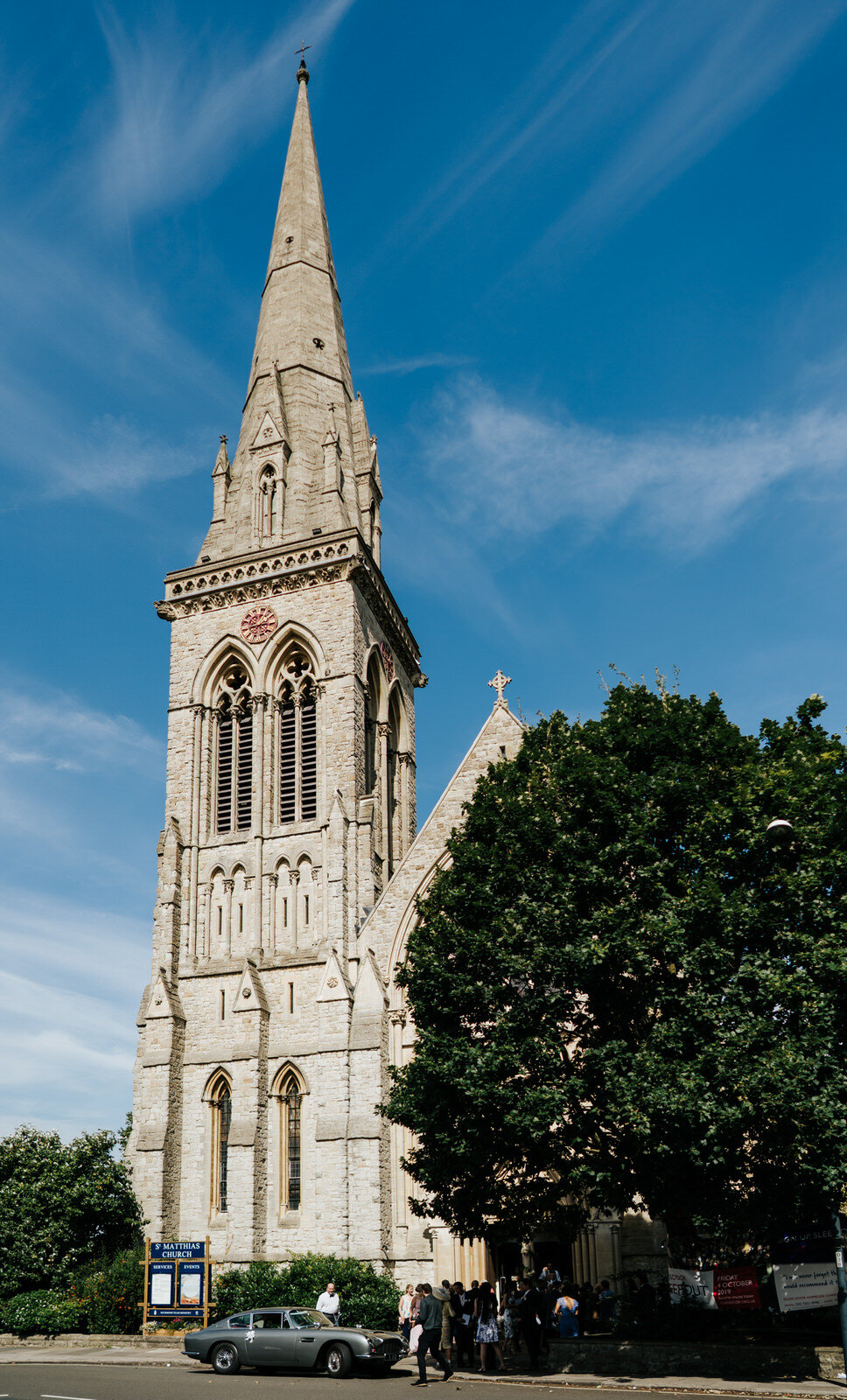 Wide photograph of the exterior of St Matthias Church in Richmond showing beautiful spire and vintage wedding car