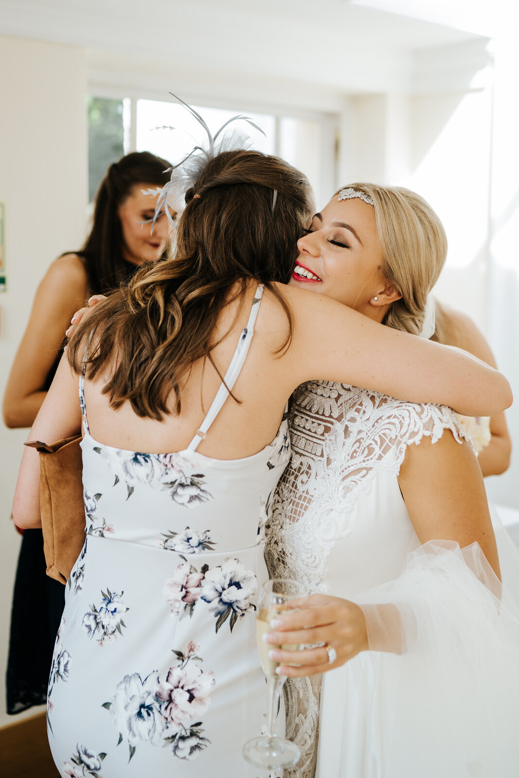 Close friend hugs bride as guests start to arrive at Pembroke Lodge for wedding celebrations