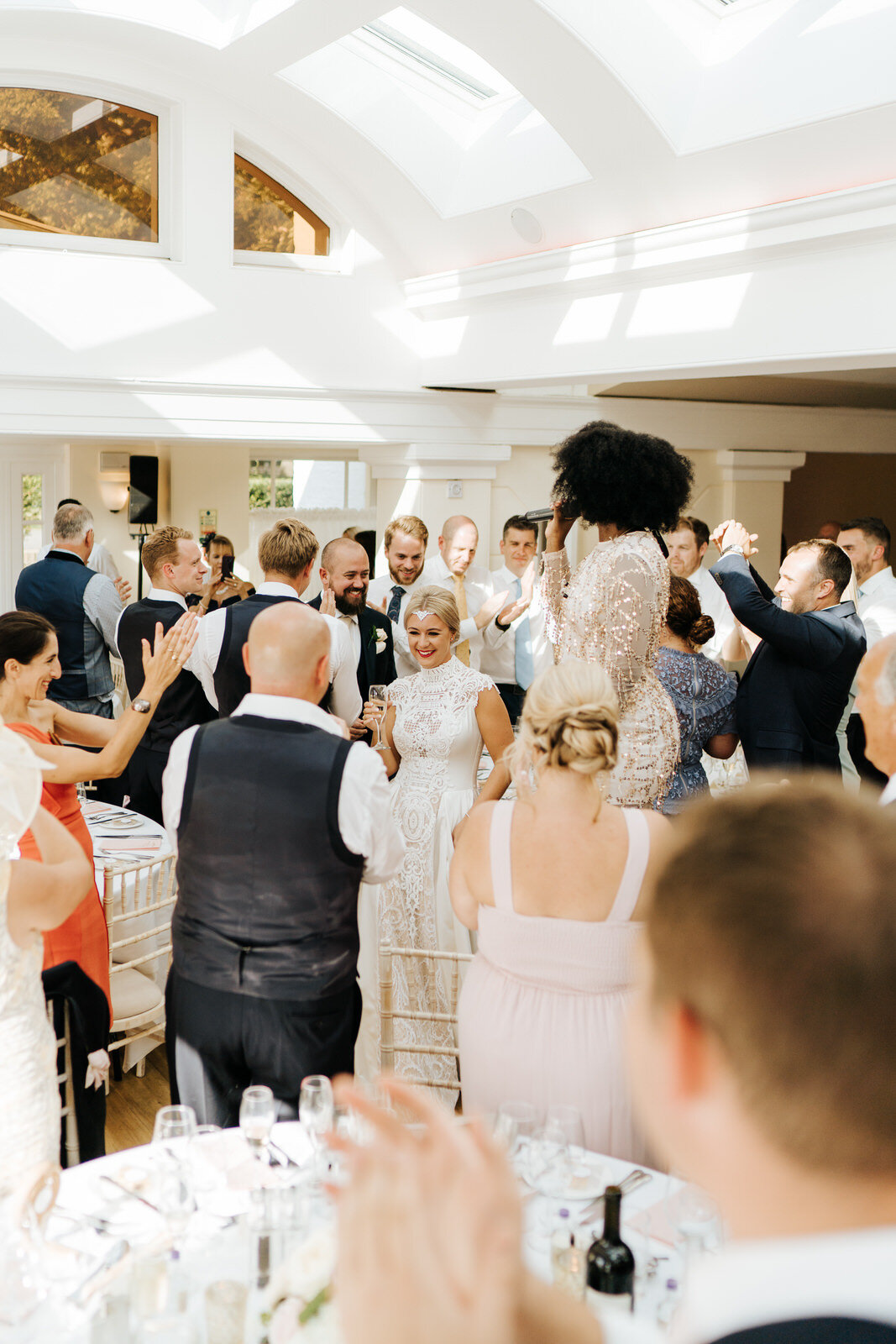 Bride and groom make their entrance into the wedding room as guests stand and cheer all around them