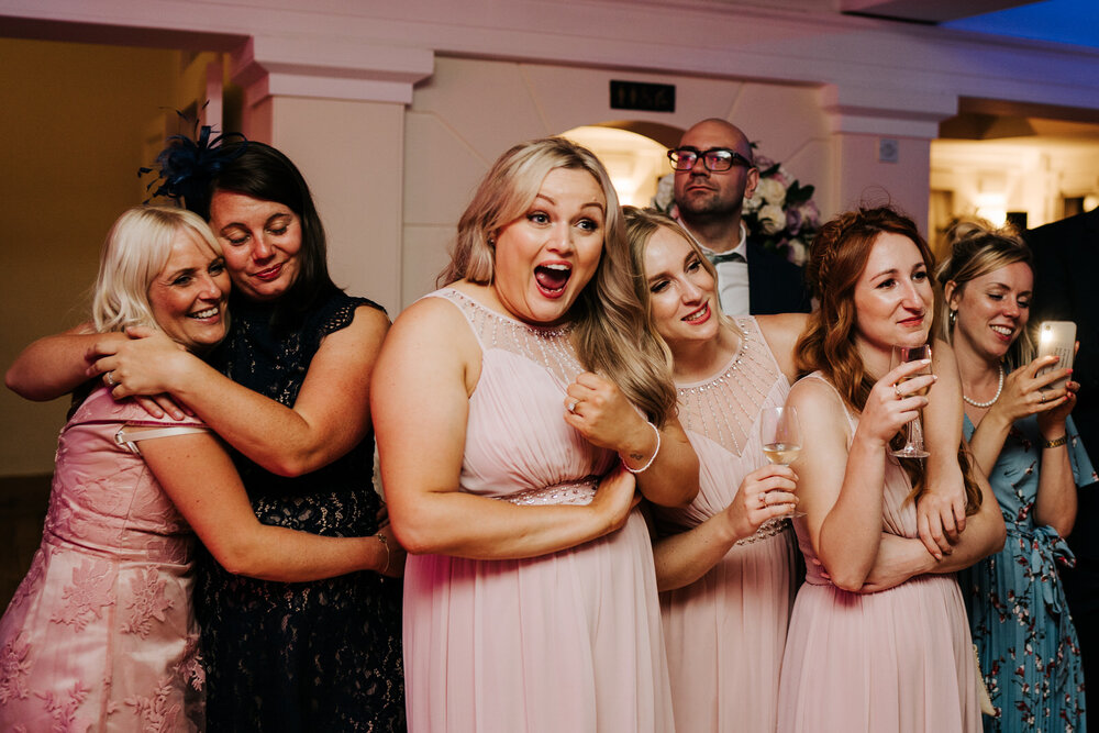 Bridesmaids and bride's girlfriends cheer on the bride and groom as they have their first dance