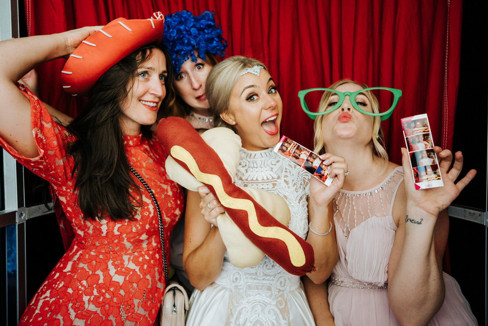 Bride poses with her friends and silly props inside photobooth at Pembroke Lodge