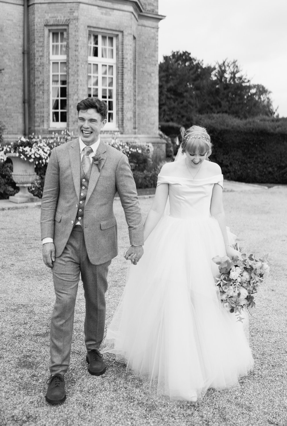 Bride and groom walk away from Hedsor House holding hands