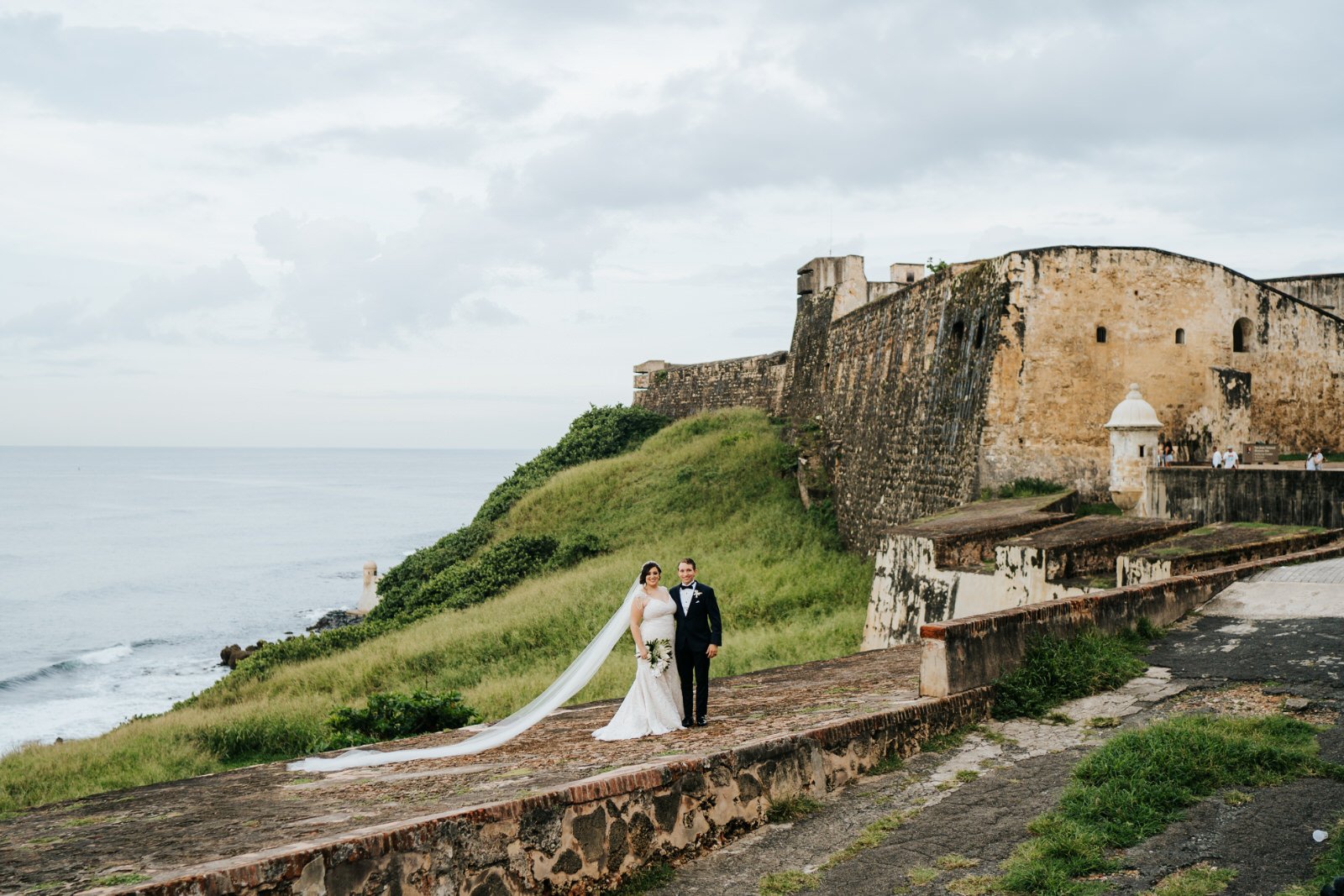 Bride and groom stand in front of fort in Old San Juan  and pose for wedding photograph