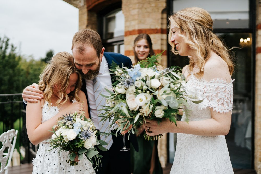 Bride and groom hug their daughter after their wedding ceremony holding Johanna Pedrick flowers at The Petersham Hotel in Richmond while bride holds pastel colour bouquet