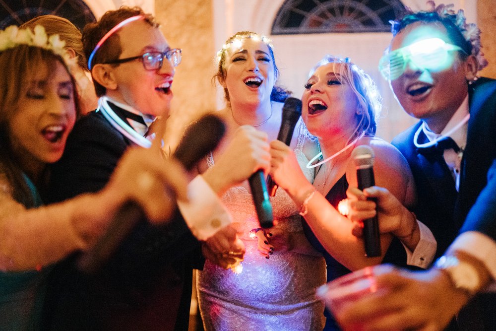 Close up photo of five people, including bride and groom, shouting and jumping during their wedding party 