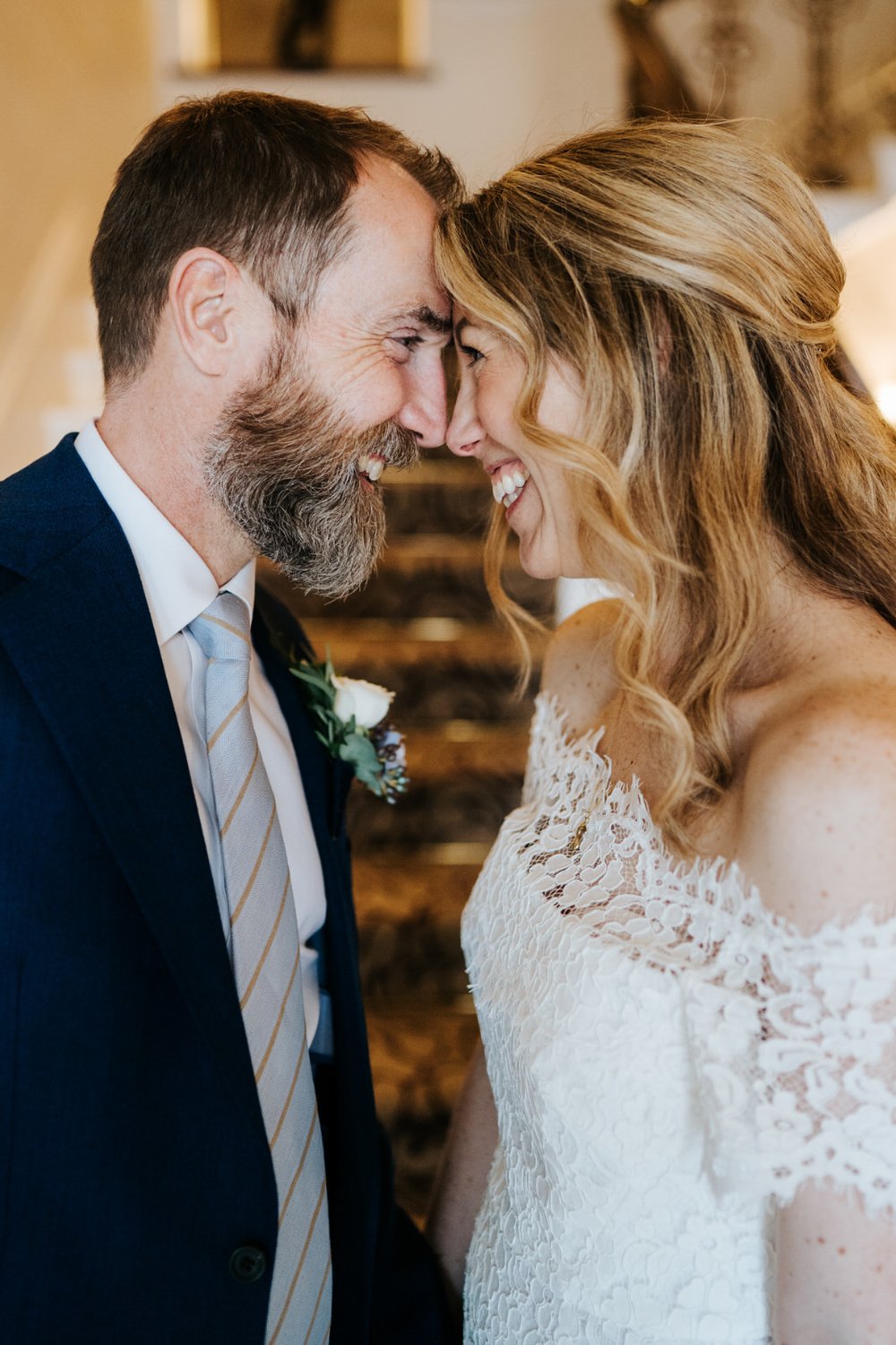 Close up photograph of bride and groom holding their faces close to each other. Both smile and look at each other intently at Petersham Hotel wedding