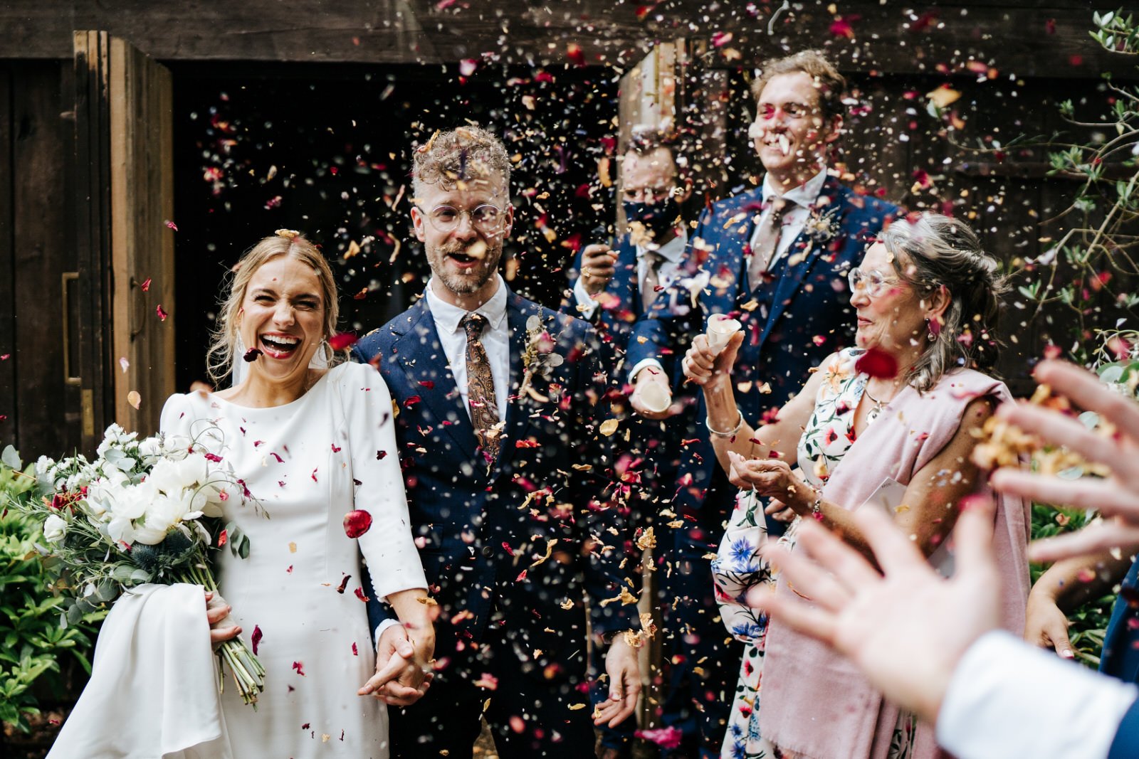 Bride and groom exit their ceremony room at Hampton Manor in Arden and are pelted by colourful confetti immediately
