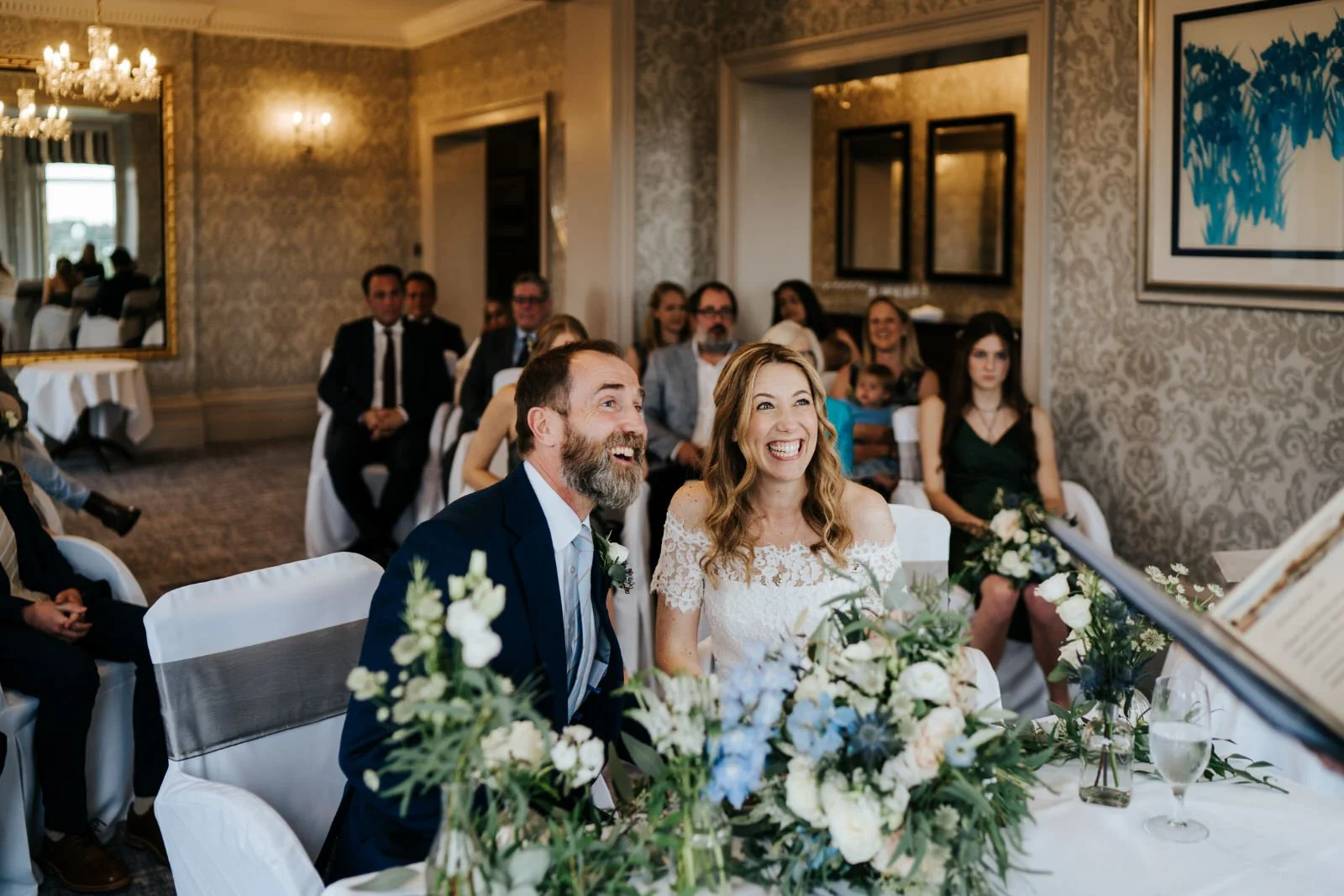 Bride and groom are sat at the registrar's table full of smiles during civil ceremony at Petersham Hotel