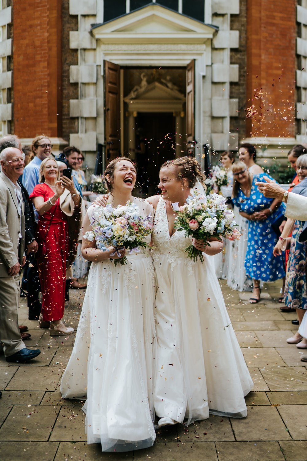 bride and bride and pelted with colourful confetti after walking out of their wedding ceremony at Orleans House Gallery