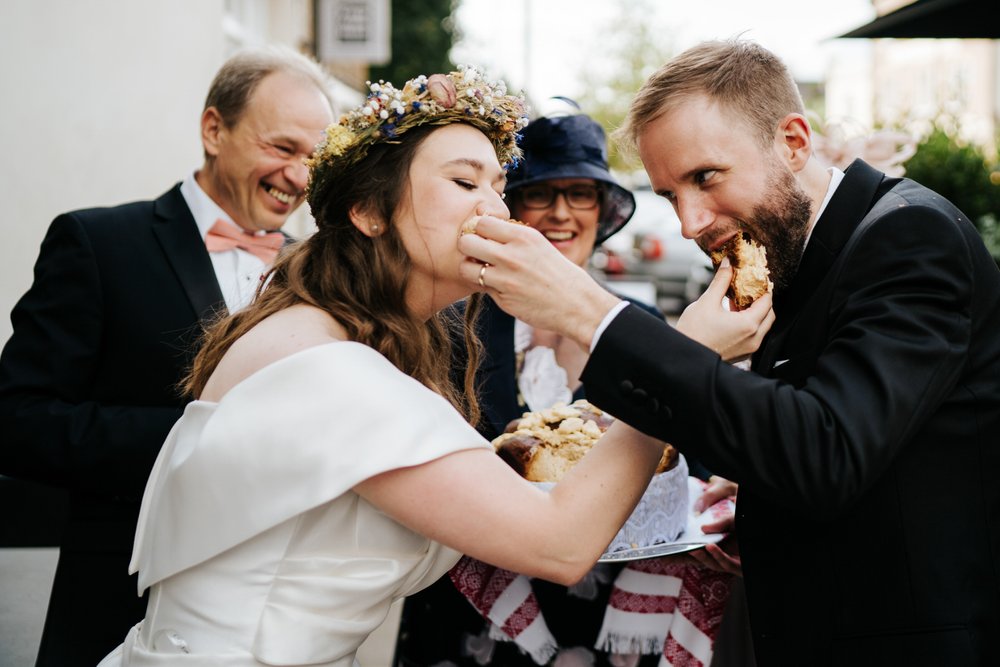 Bride and groom feed each other a piece of bread in Ukrainian wedding tradition
