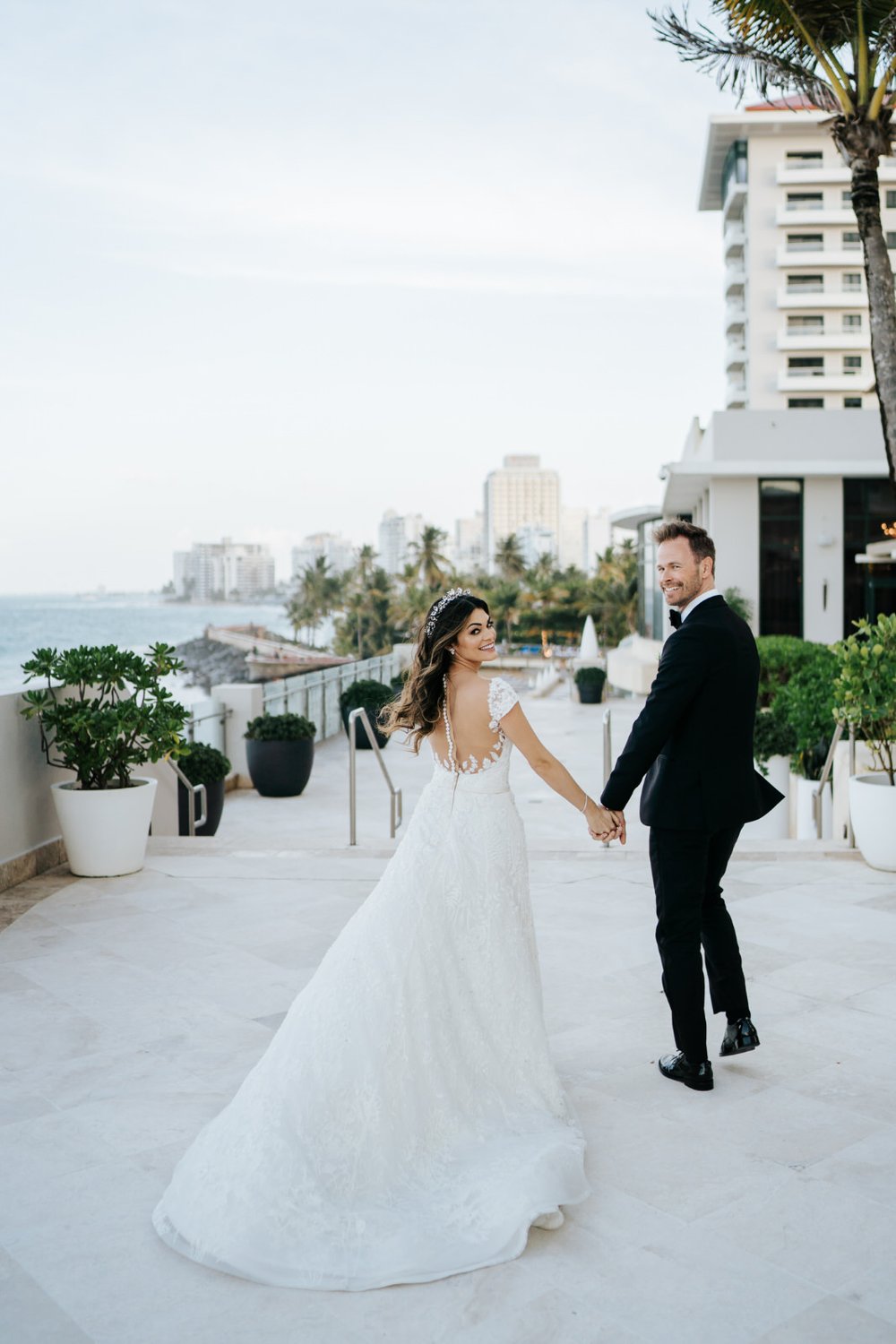 Bride and groom walk away from the camera as gust of wind hits groom's hair at Puerto Rico wedding venue Vanderbilt Hotel