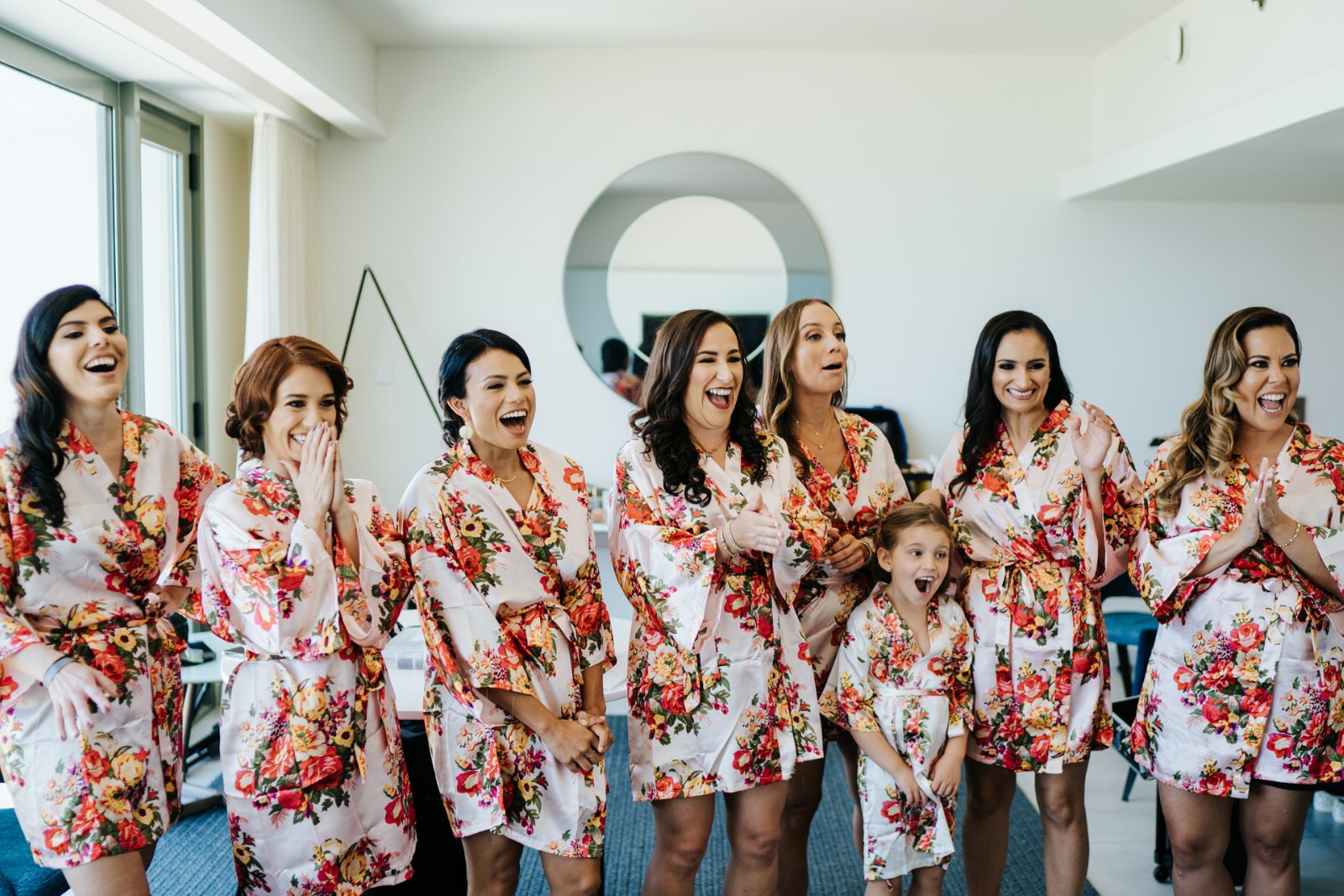 Eight bridesmaids gasp in awe as bride, off camera, reveals what her wedding dress looks like