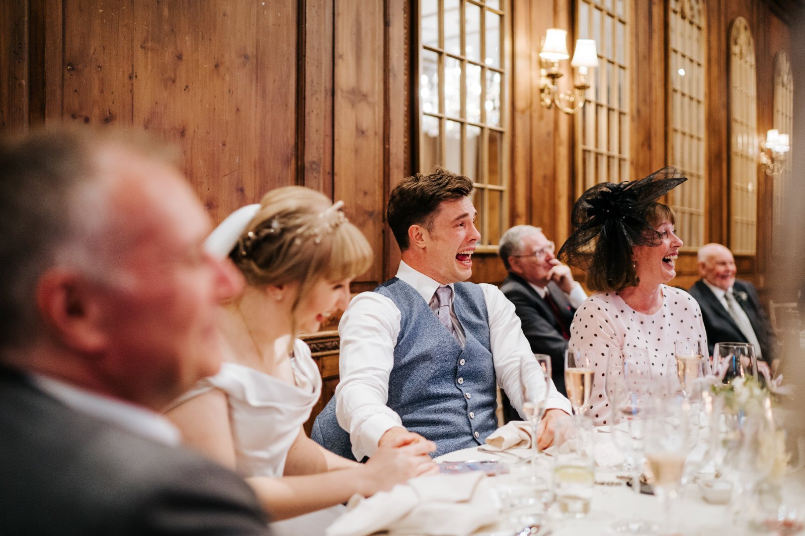 Bride, groom and their parents cannot contain their laughter during wedding speeches