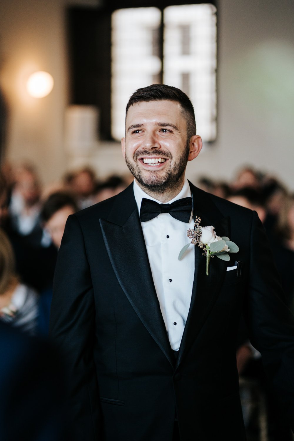 Portrait of groom as he stands and smiles after seeing bride during The Queen's House London wedding ceremony