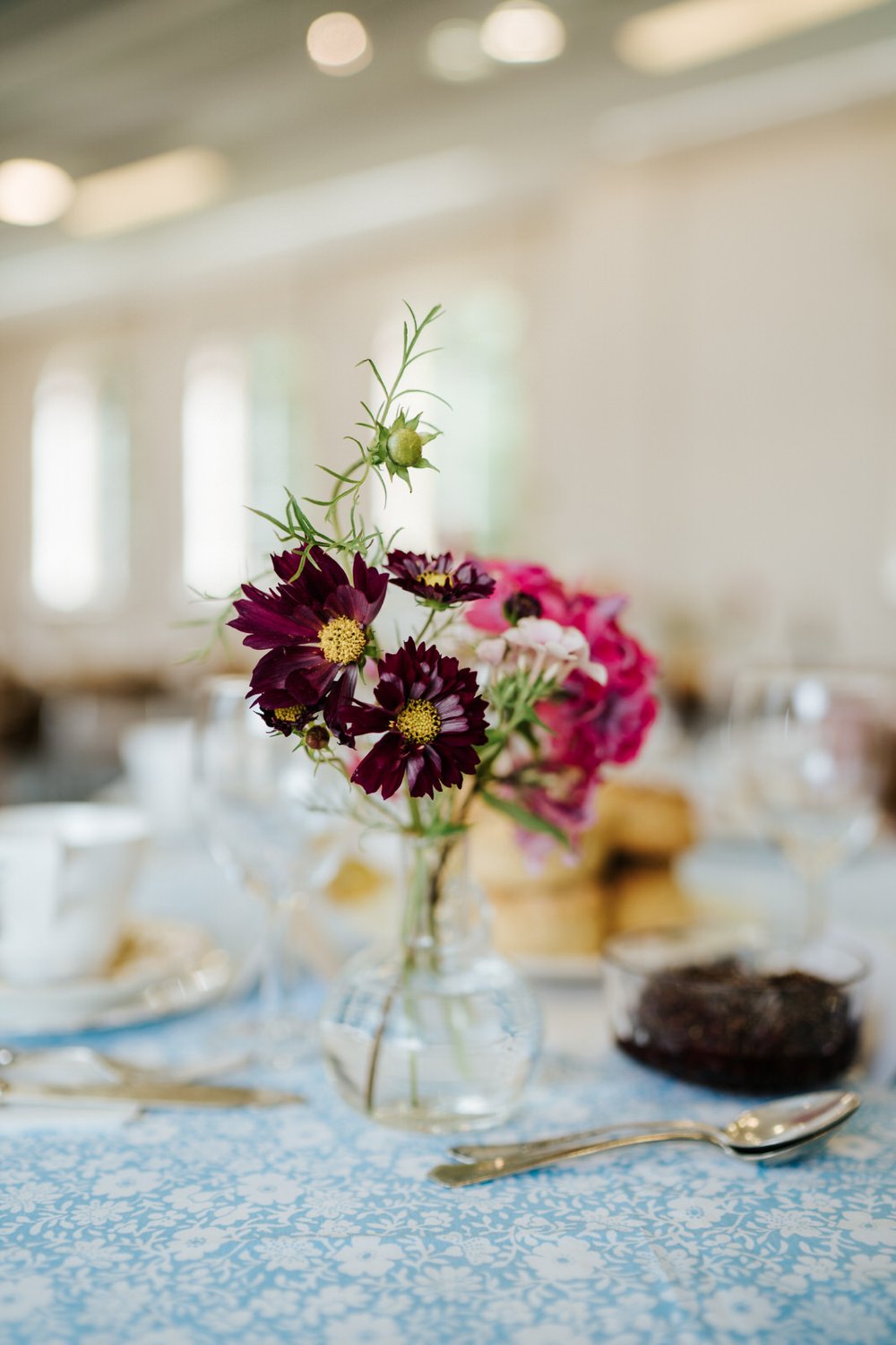Violet and purple flowers in small vase on table during Orleans House Gallery wedding reception at The Stables