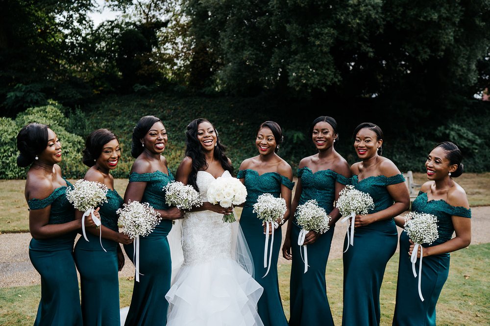Bride and her bridesmaids share a moment of laughter while posing with their elegant, round, white rose bouquets by Louise Dutfield during Syon Park Wedding