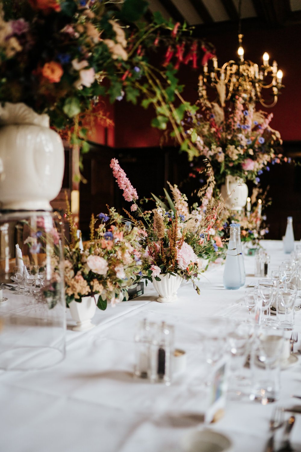 Centrepiece of colourful and rustic flowers on top of head table at Jesus College in Cambridge 
