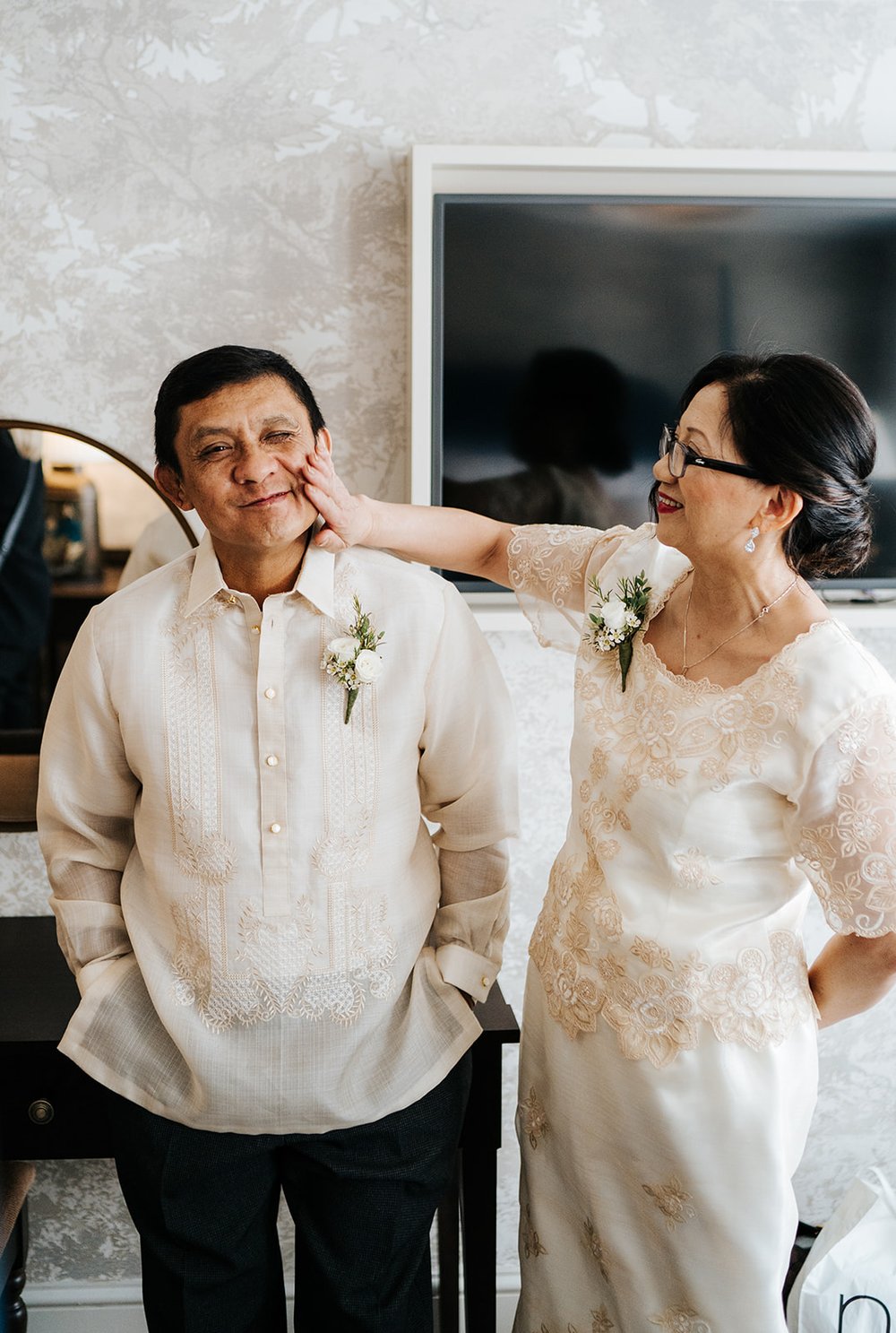 Bride's mother grabs her husband's cheek before leaving for wedding ceremony at bingham riverhouse