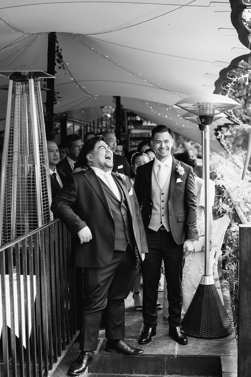 Groom and his best man captured in candid moment of laughter in black and white photograph