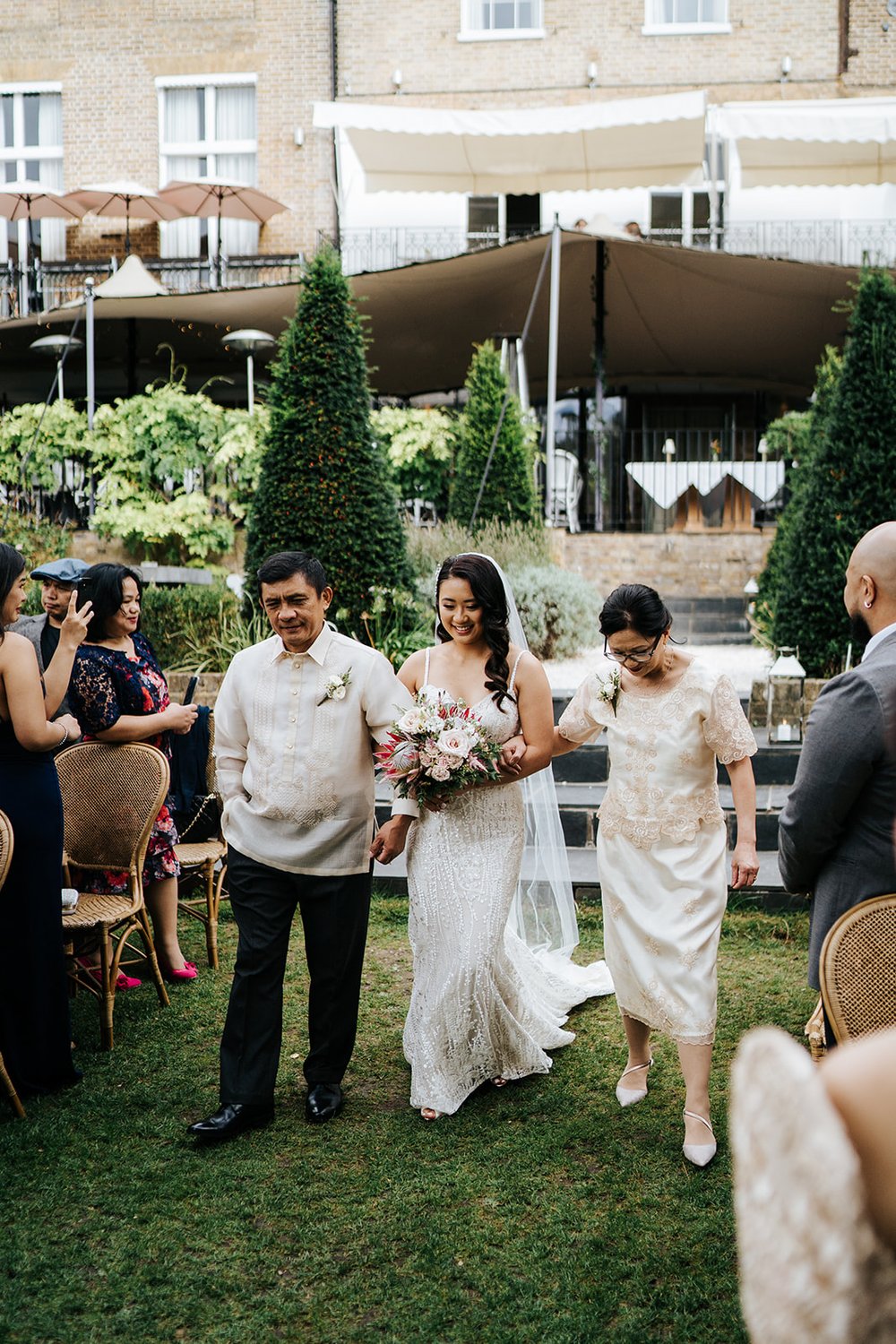 Bride walks down the aisle in Bingham Riverhouse wedding and is flanked by father and mother