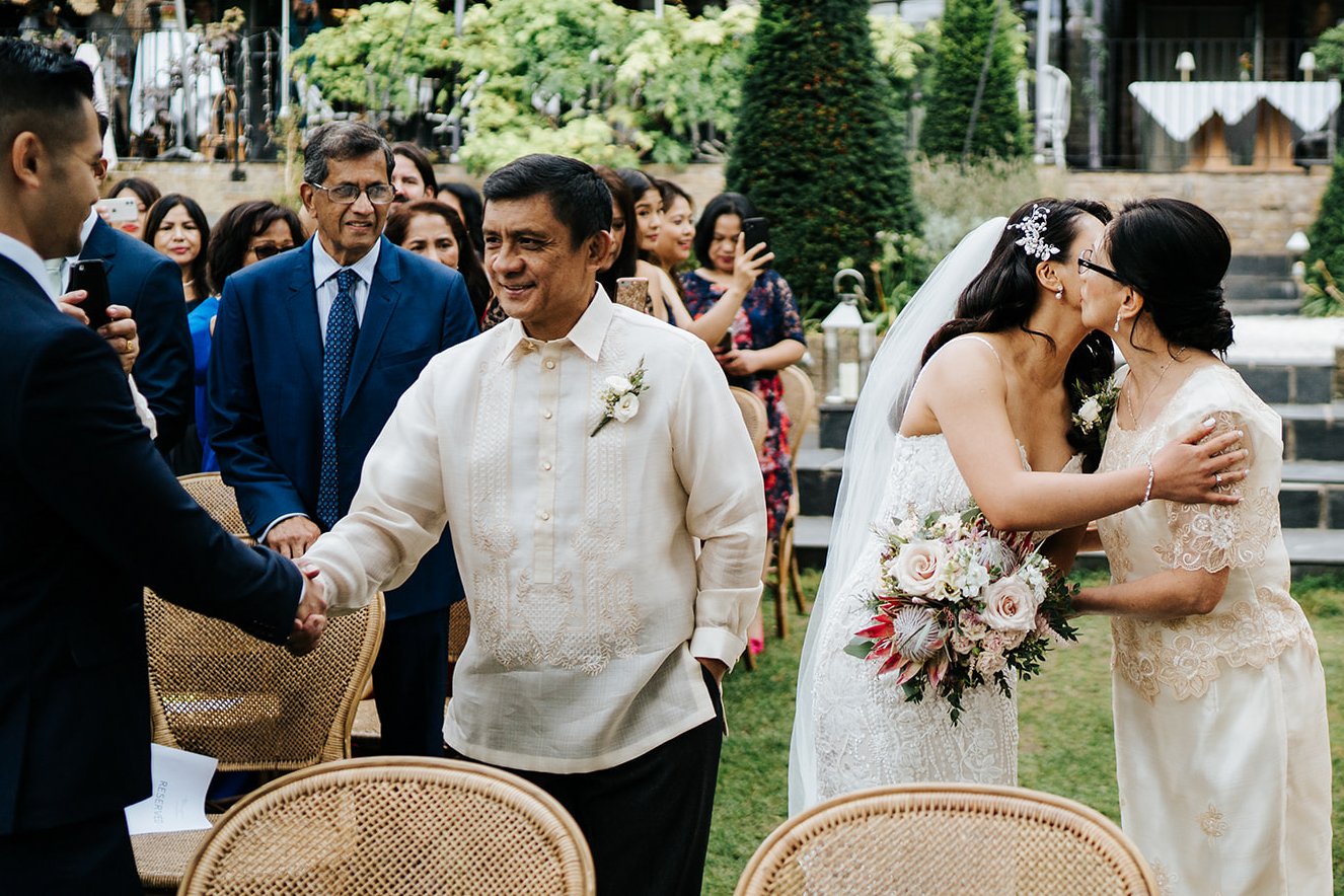 Groom shakes father of the bride's hand while bride kisses and embraces her mom at the top of the aisle in outdoor Bingham ceremony