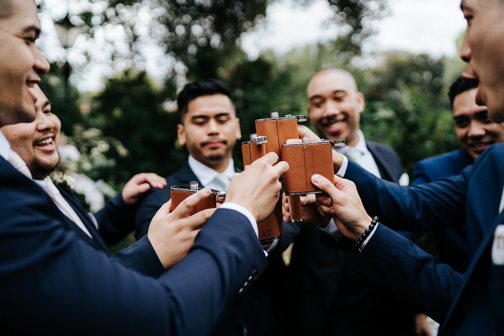Groom and his groomsmen take a moment to toast with whiskey flasks after ceremony