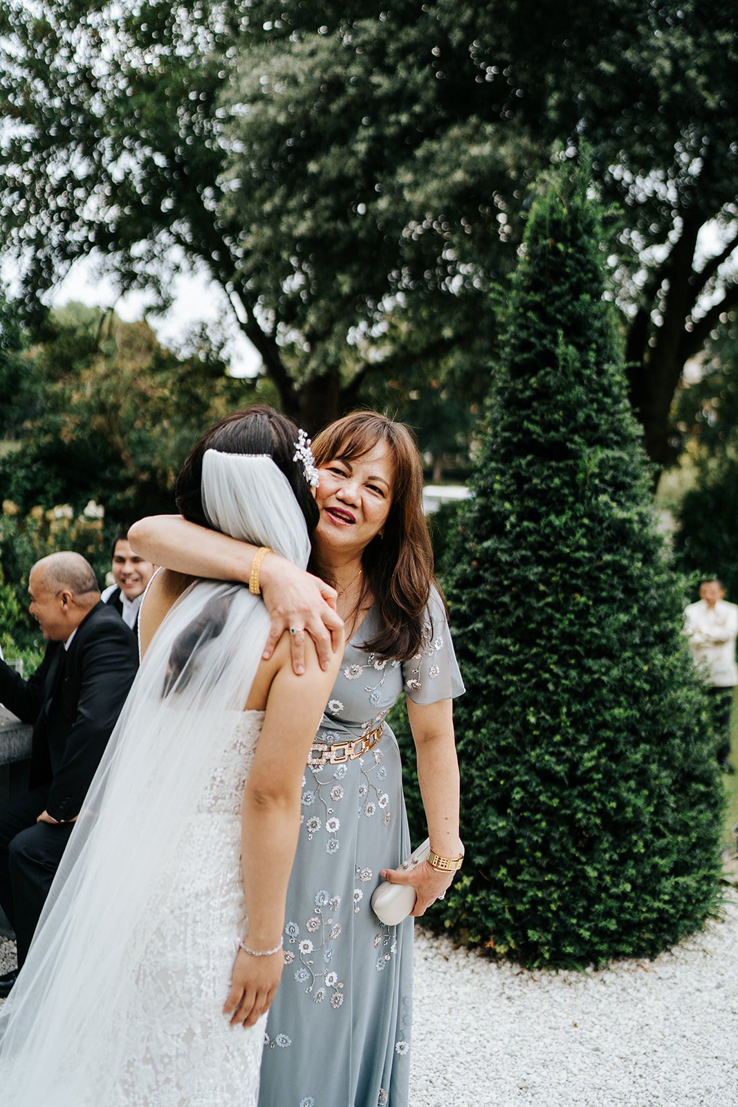 Bride hugs a close acquaintance as they both smile during tender post-ceremony moment 