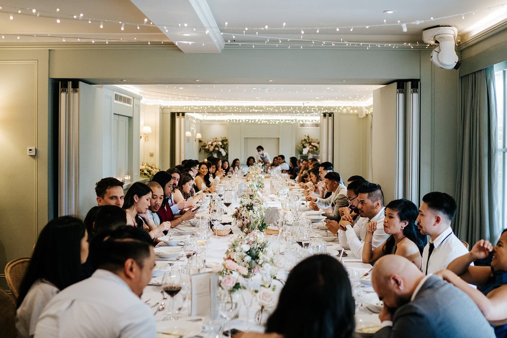 Wide photograph of guests sat at the table enjoying their food and drink at Bingham Riverhouse Wedding in Richmond, London