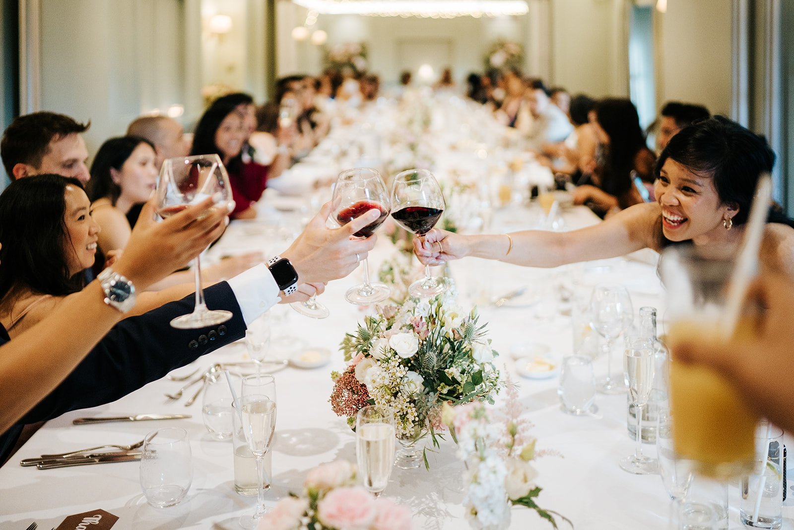 Atmospheric shot of glasses clinking during wedding toasts