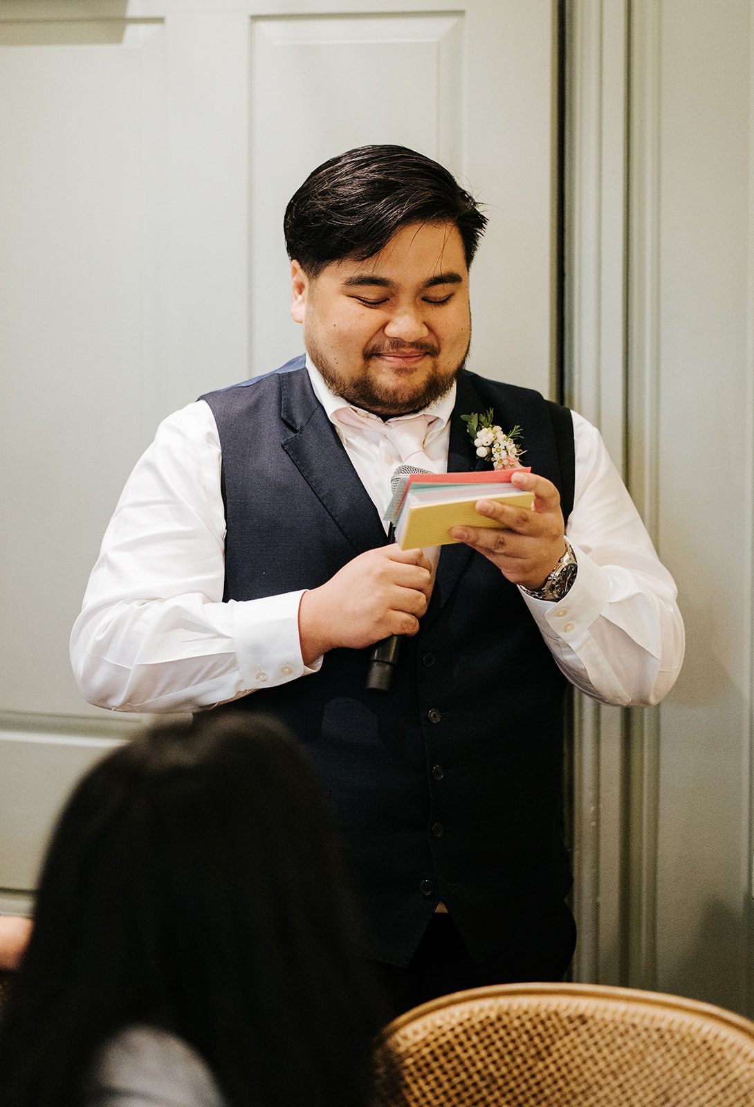 Best man looking down at his notes as he stands and delivers wedding speech 