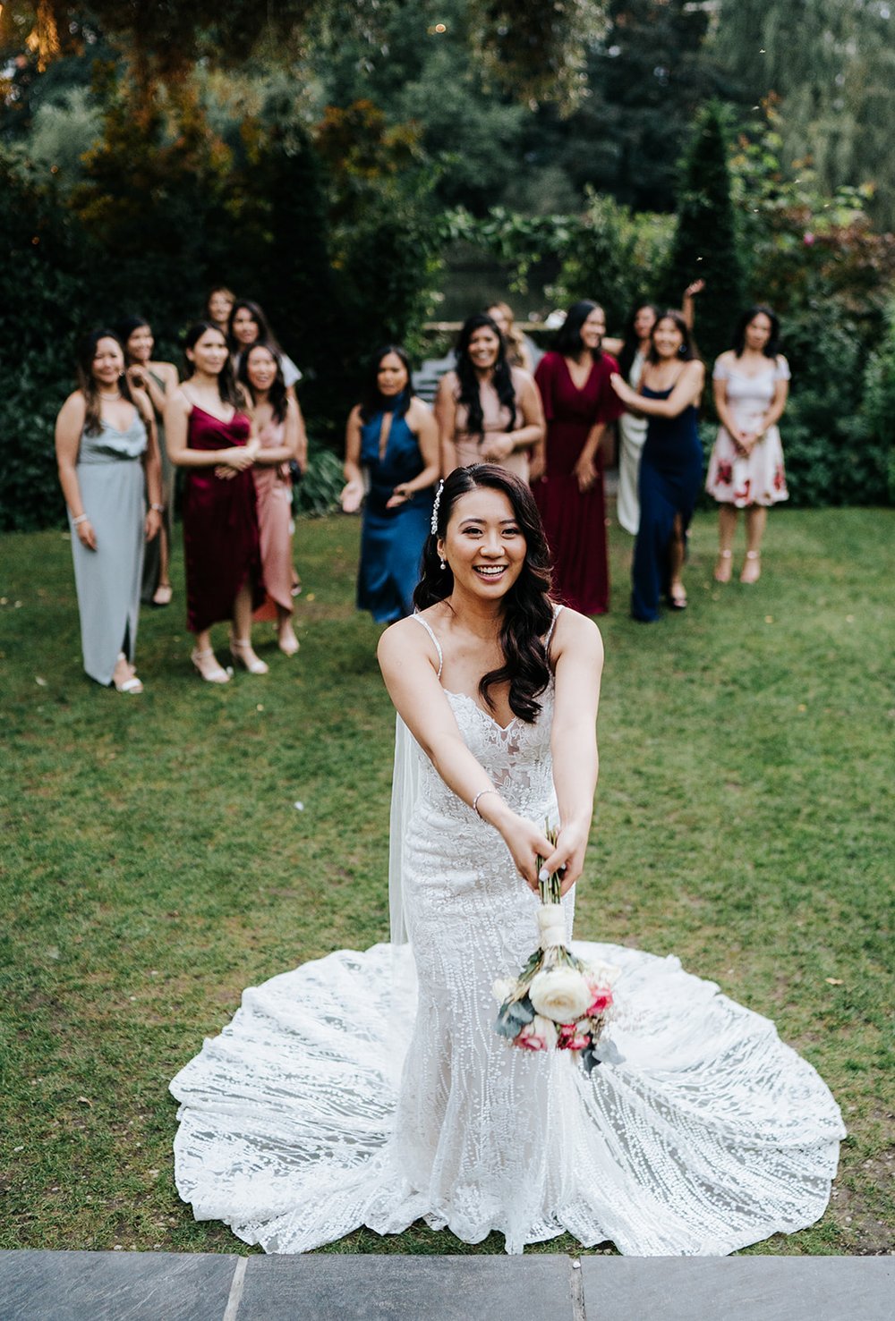 Bride throws bouquet towards friends standing behind her ready to catch it 